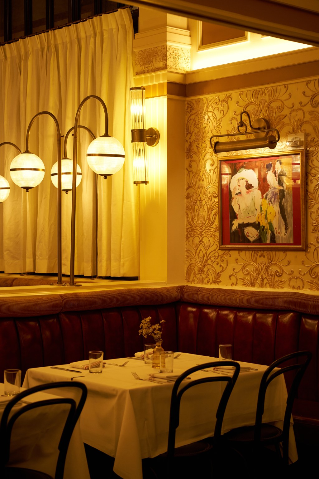 The chandelier-lit dining room of Delphine Brasserie, with mirrored panels and ornate wallpaper